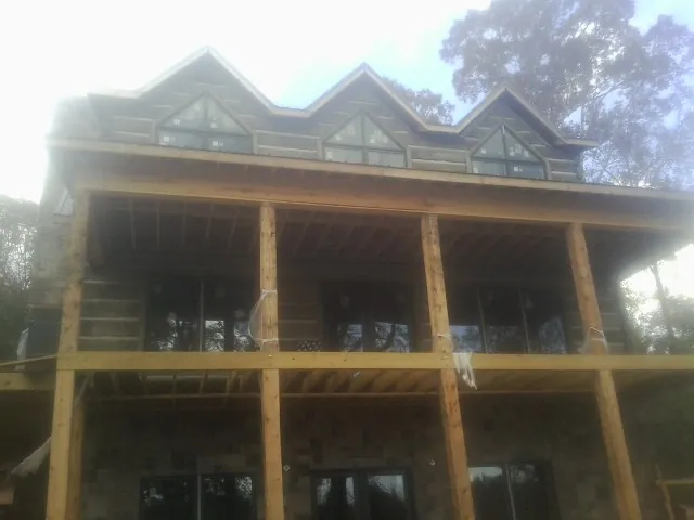 Dormers and porch framing on a large log home under construction — Roof Coating work by our crew in Macomb